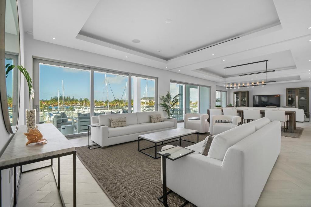 un soggiorno con divani bianchi, tavoli e finestre di Casablanca Bahamas- New Luxury Waterfront Condo, Palm Cay, The Bahamas a Nassau