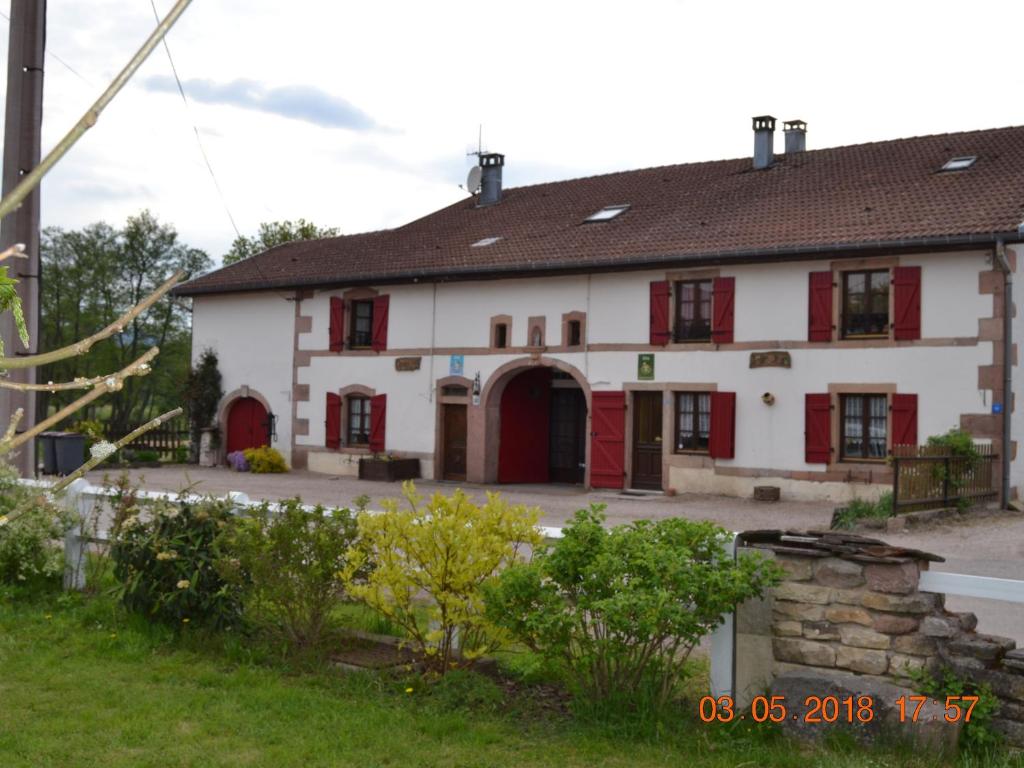 un grand bâtiment blanc avec volets rouges dans l'établissement Gîte authentique avec terrasse couverte, 16 km de Gérardmer, 4 chambres, équipement bébé, Wi-Fi inclus - FR-1-589-231, à Aumontzey