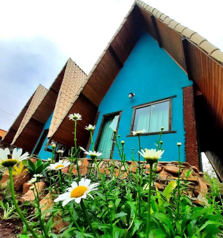 a blue house with flowers in front of it at Pousada Contos da Lua Vaga in Milho Verde