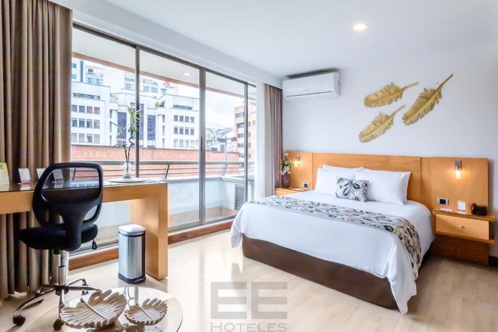 um quarto de hotel com uma cama, uma secretária e uma janela em Leblón Suites Hotel em Medellín