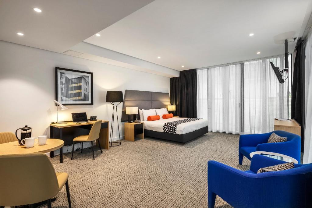 シドニーにあるクエスト セント レナーズのベッド、デスク、椅子が備わるホテルルームです。
