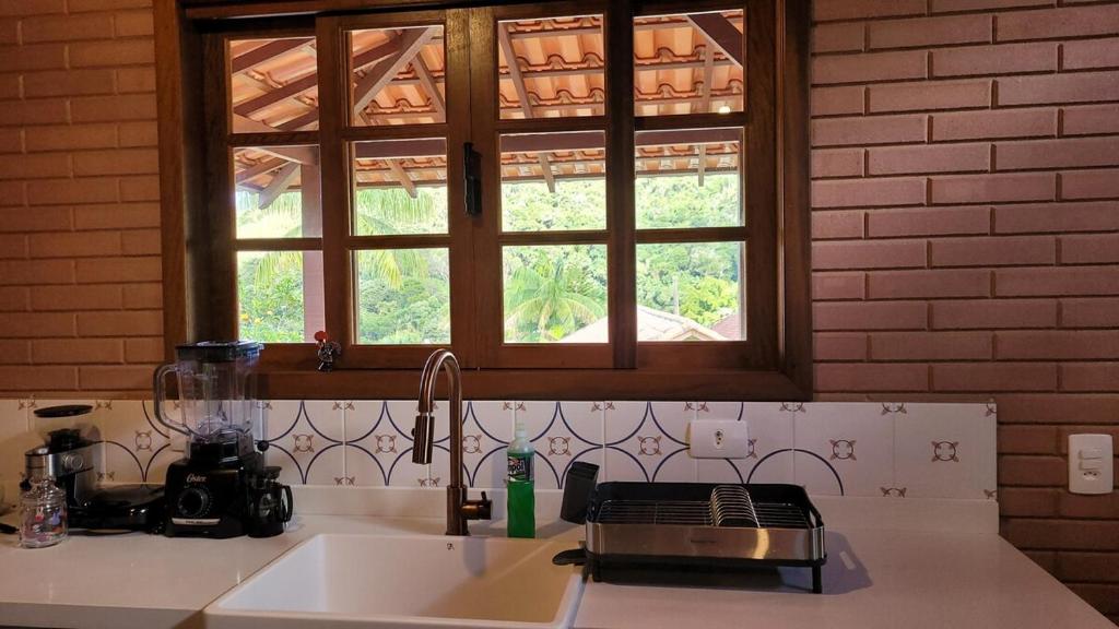 Una encimera de cocina con un fregadero y una ventana. en Casa charmosa no centro de São Pedro da Serra, en Nova Friburgo