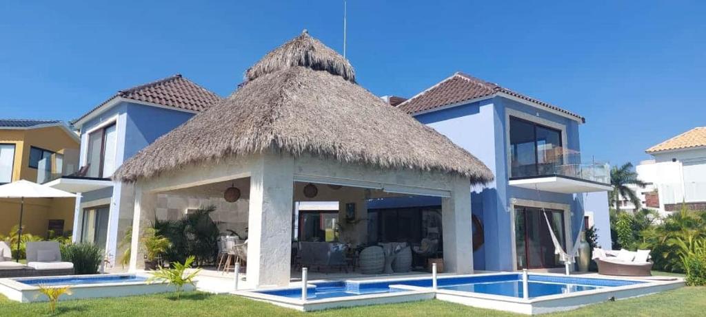 a villa with a thatch roof and a swimming pool at Naisári Residencia Punta de Mita María Bonita in Higuera Blanca