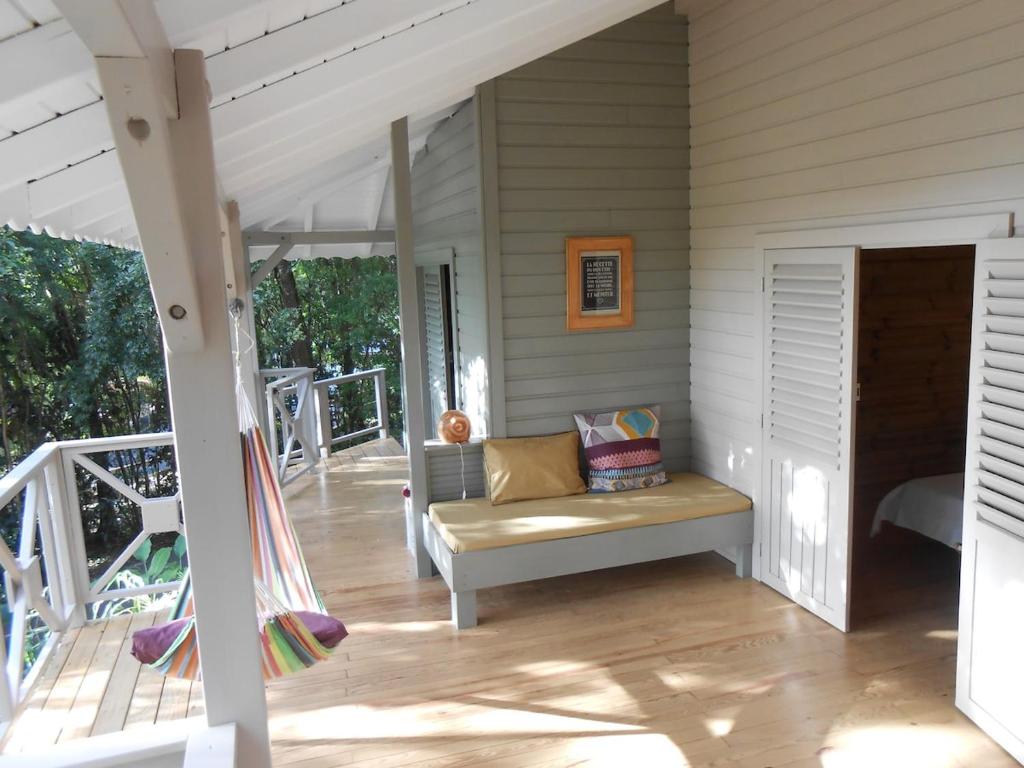 a porch of a house with a bench on the porch at Nati Lodge - Bungalow Guadeloupe in Bouillante