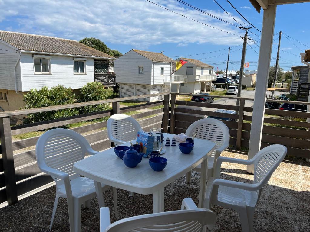 - une table blanche avec des chaises et des plats bleus dans l'établissement Coquet Chalet à 50m de la Plage - 6 Pers, Terrasse, TV, Lave-vaisselle - FR-1-796-42, à Gruissan