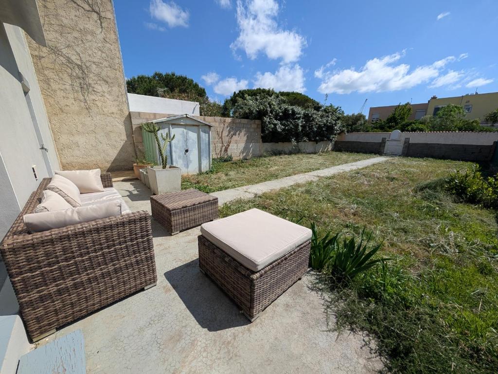 un patio avec deux chaises en osier et un pouf dans l'établissement Maison T4 110m² avec jardin clos, à 1500m de la plage - FR-1-797-60, à Port-la-Nouvelle