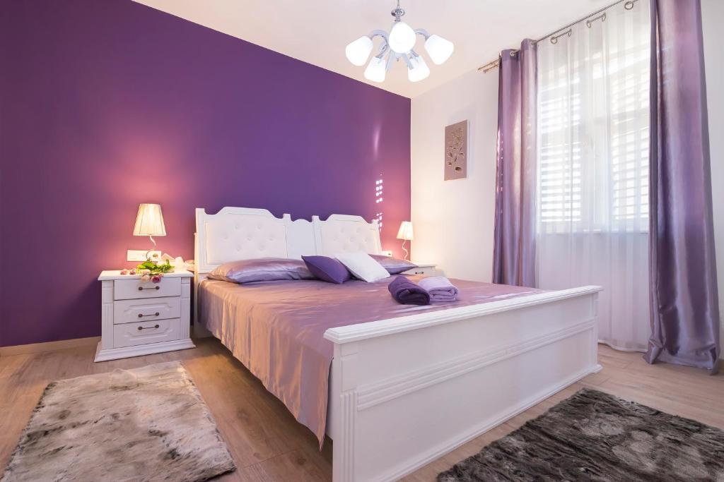 sypialnia z dużym łóżkiem i fioletowymi ścianami w obiekcie Apartments J&J w Splicie