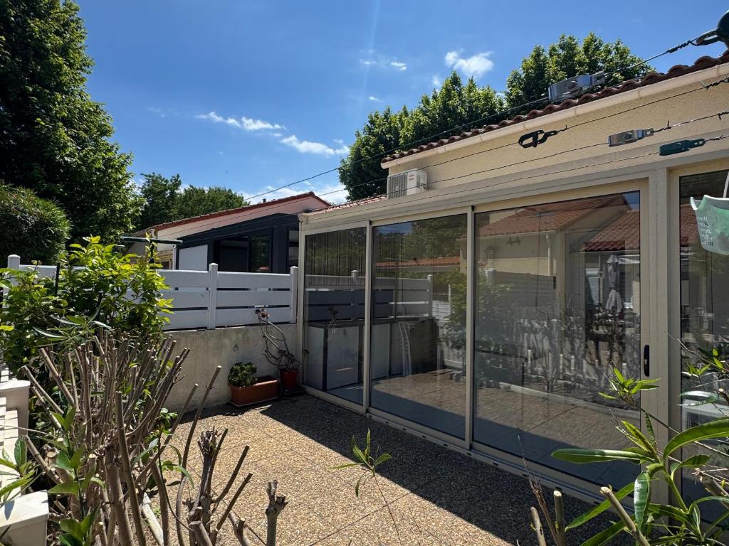 une véranda avec des portes vitrées dans un jardin dans l'établissement Pavillon lumineux climatisé à 800m de la plage avec loggia et terrasse - 5 couchages - FR-1-732-16, à Argelès-sur-Mer
