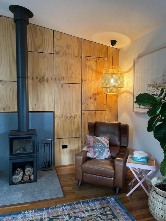 sala de estar con silla de cuero y estufa de leña en Beach Vibes Accommodation, en Scotts Head