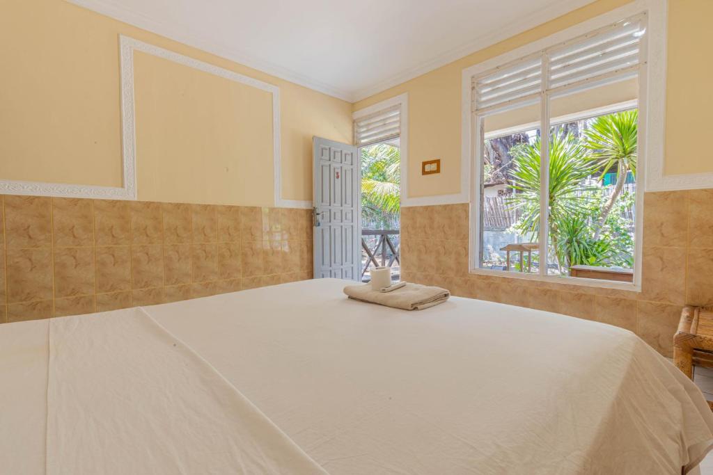 Funny Homestay 2 في غيلي تراوانغان: غرفة نوم بها سرير أبيض كبير مع نافذة