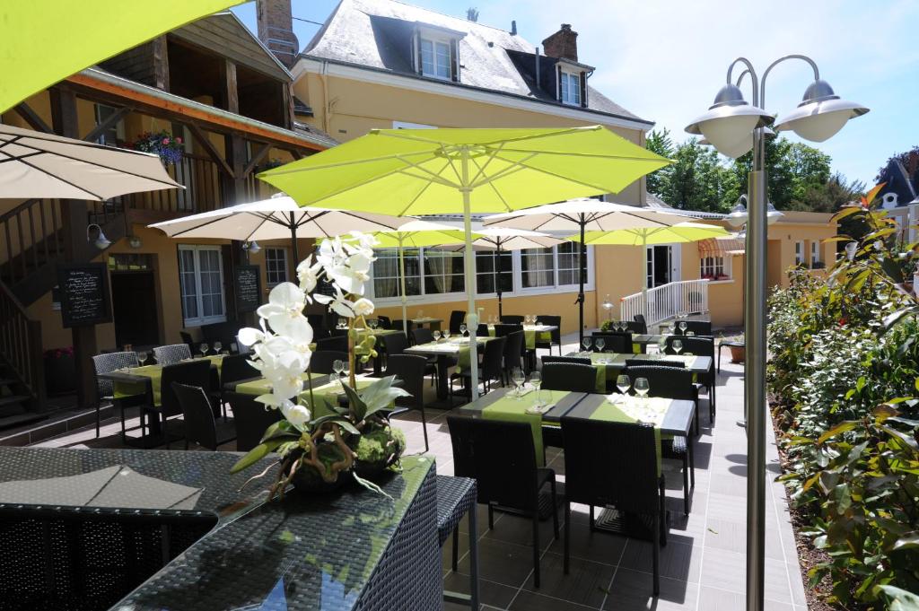 een restaurant met tafels, stoelen en parasols bij Hôtel Saint Jacques in Thorigné-sur-Dué