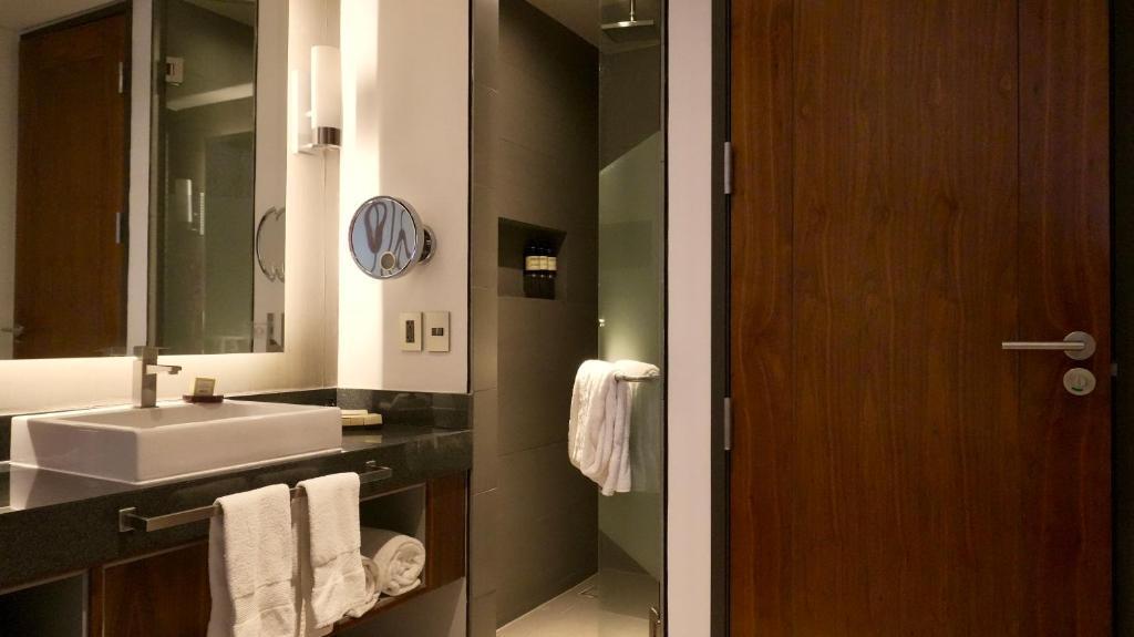 A contemporary bathroom has a wide vanity, illuminated mirror, and separate glass shower area.