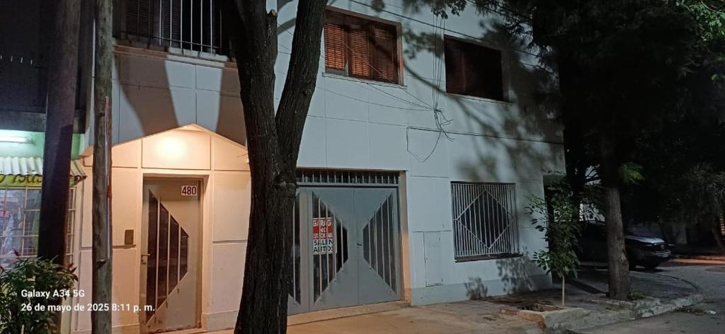 a white building with a door and a tree at Departamento Peru y Borges in Santiago del Estero
