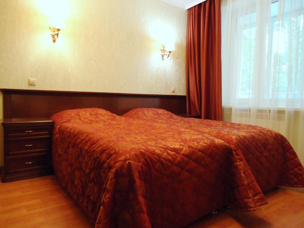 1 dormitorio con 1 cama con edredón rojo y ventana en Apart-Hotel Nagornoe, en Khimki