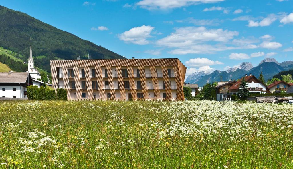 a building in the middle of a field of flowers at Apartments Dolomit-Royal in Sillian