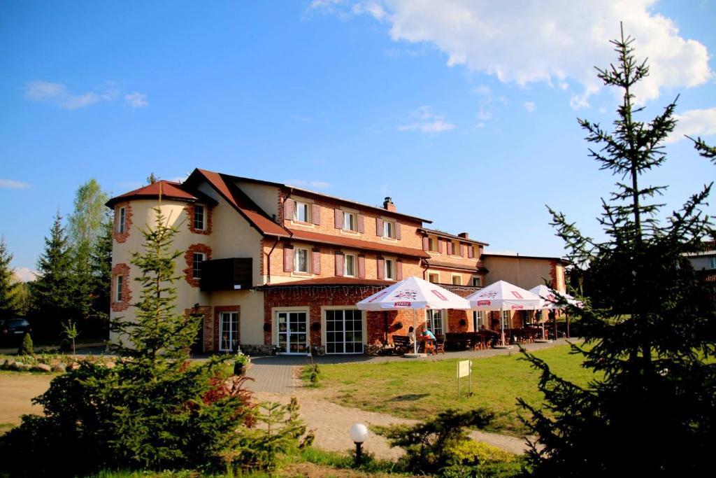 a large building with umbrellas in front of it at Hotelik Wulpink Majdy Olsztyn in Majdy