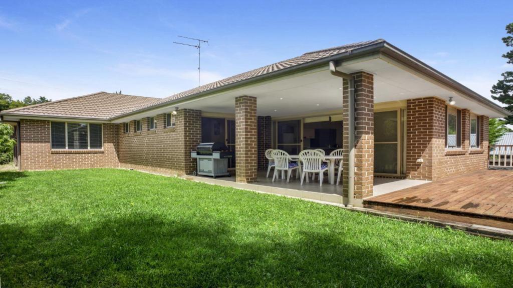 a brick house with a deck and lawn at Refresham Katoomba South in Katoomba