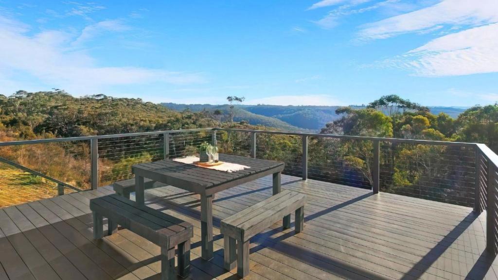 a wooden deck with a table and bench on a balcony at The Wentworth Backing Blue Mountains National Park in Wentworth Falls