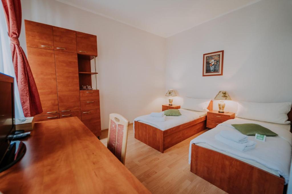 a bedroom with two beds and a wooden table at The Rooms by Dalia in Košice
