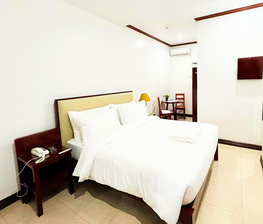 a bedroom with a large white bed and a phone at SANJH Island Hotel powered by Cocotel in Roxas