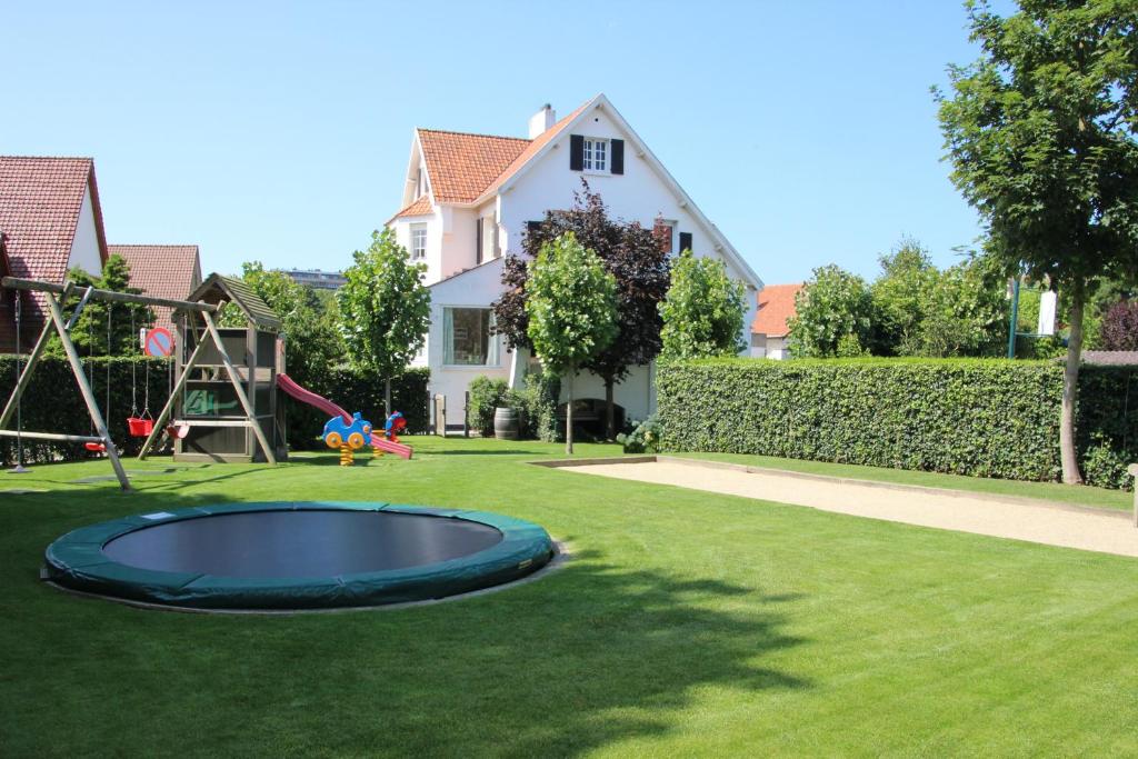 einen Hof mit einem Trampolin und einem Spielplatz in der Unterkunft Villa Dageraad in De Panne