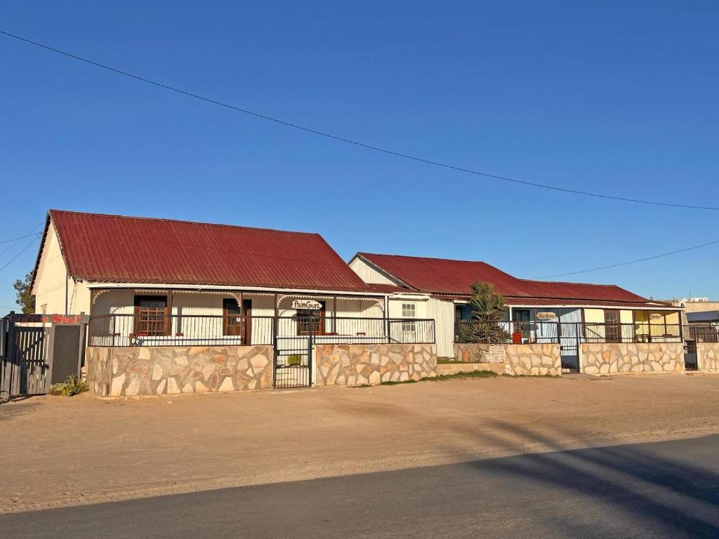 a building with a stone fence in front of it at Grazia Cottages in Port Nolloth
