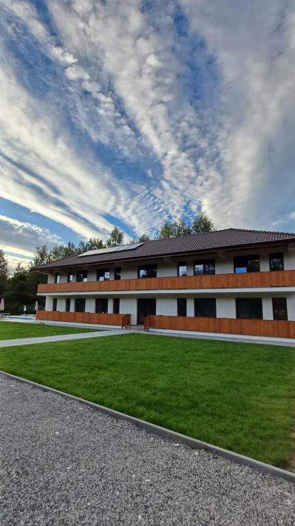 un edificio con un césped verde delante en Complexul Rustic, en Avrig