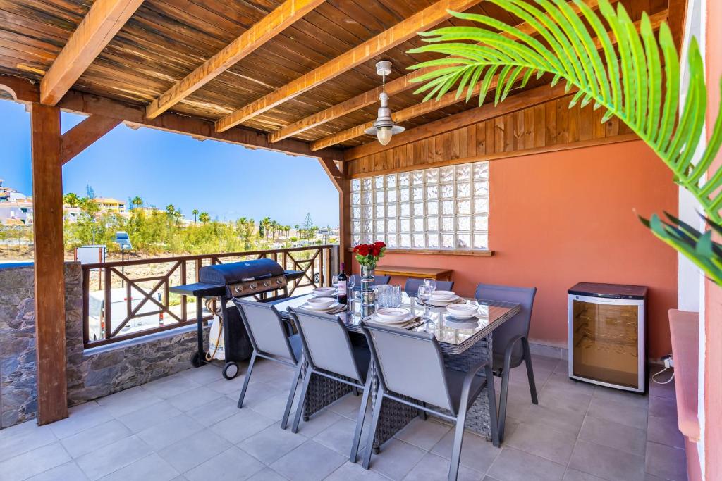 a dining room with a table and chairs on a patio at Arguineguín Villa Hot Tub, BBQ & Views in Patalavaca