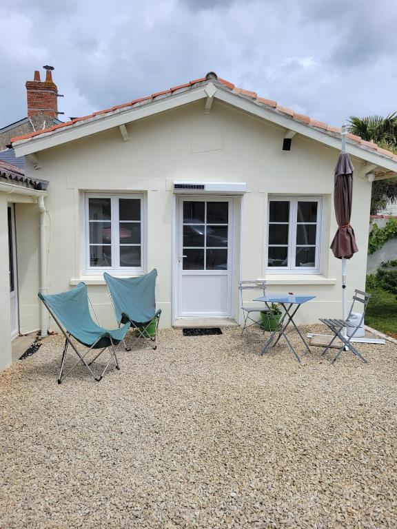 2 chaises et un parasol devant une maison dans l'établissement Logis du Pey Roux Accueil Vélos, à Saint-Jean-de-Monts