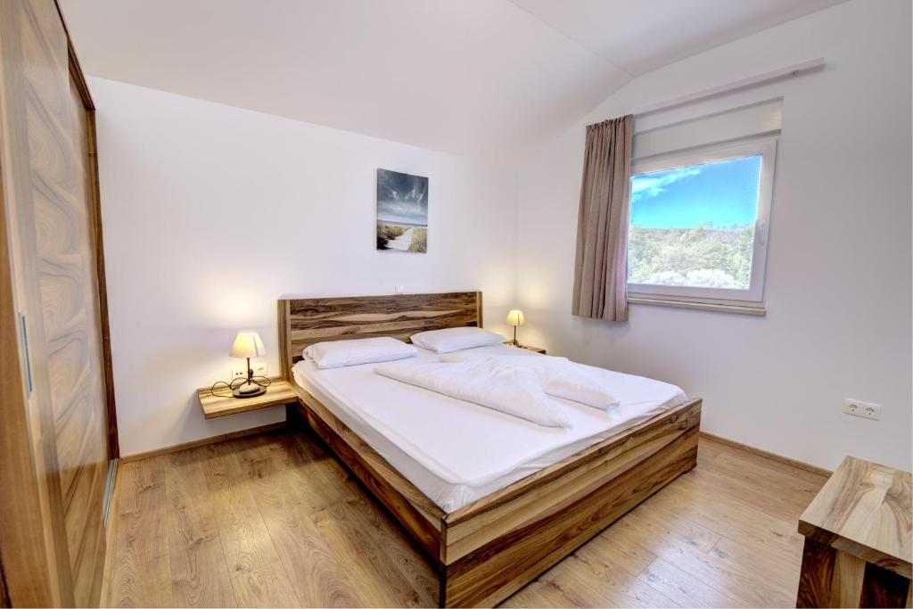 a bedroom with a bed with white sheets and a window at Cool Šilo Appartement Resort in Šilo