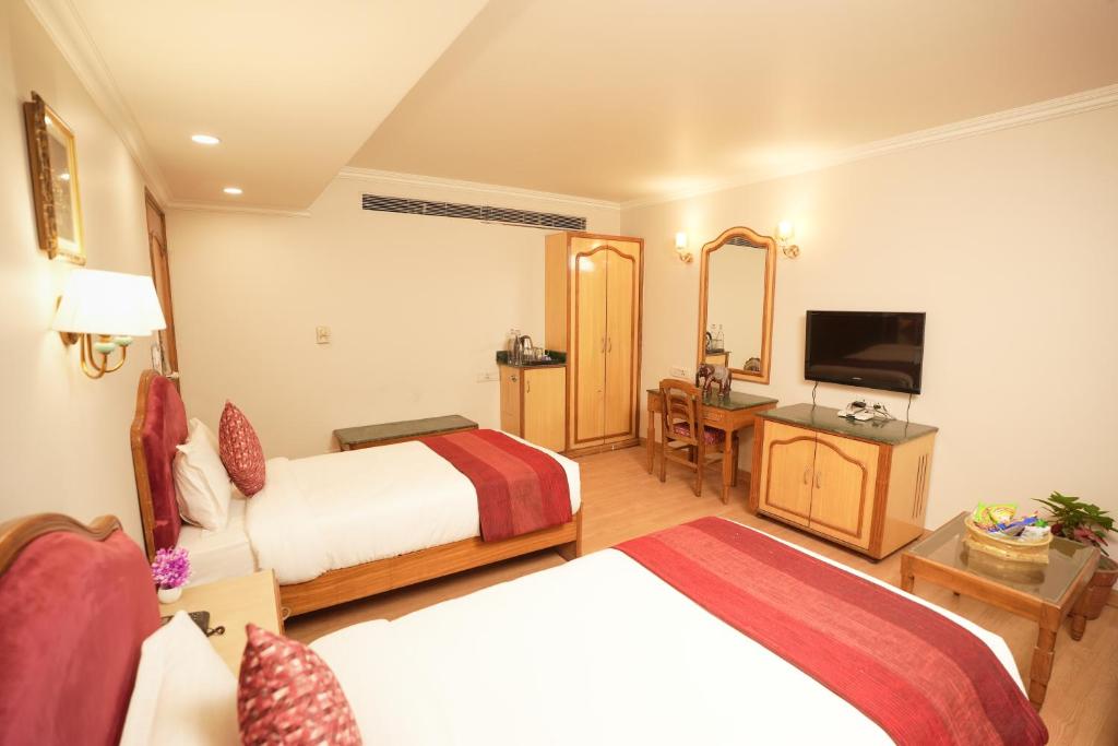 una camera d'albergo con due letti e una televisione di Hotel Surya Residency, Amritsar ad Amritsar