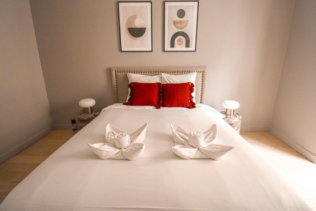 une chambre avec un lit blanc avec des oreillers rouges dans l'établissement Appartement cosy Tour Eiffel-Invalides, à Paris