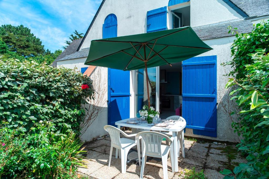 una mesa con 2 sillas y una sombrilla verde en Locmariaquer Mer & Plage - à 50m de la plage, en Locmariaquer