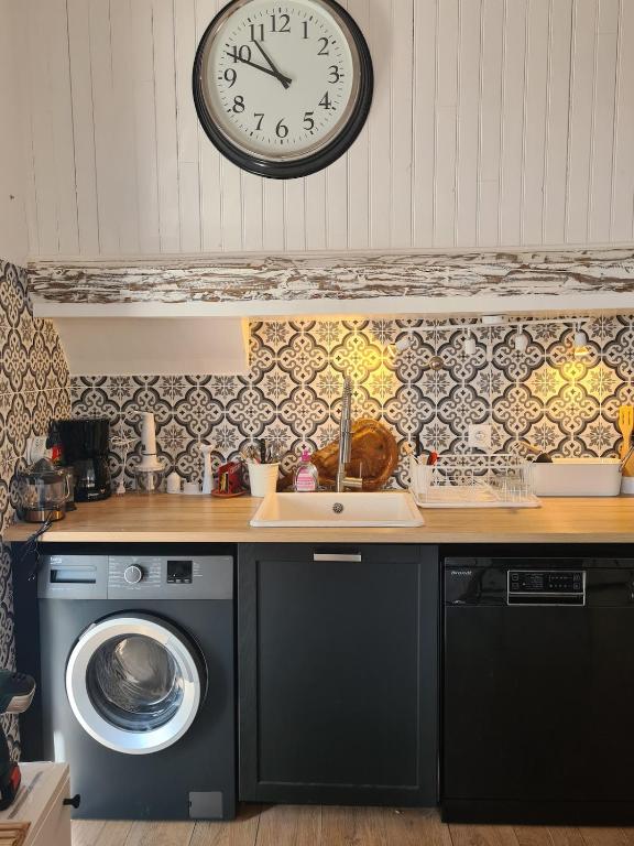 une cuisine avec une machine à laver et une horloge au mur dans l'établissement tout près du canal royal et des halles, à Sète