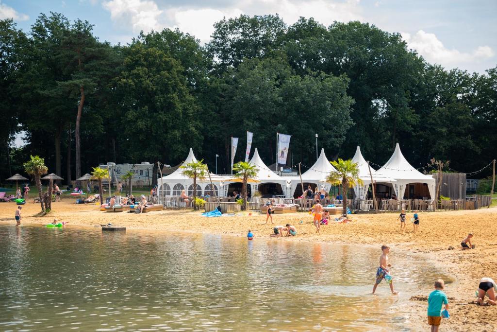 Un grupo de personas en una playa con tiendas blancas. en Vakantiepark BreeBronne, en Maasbree
