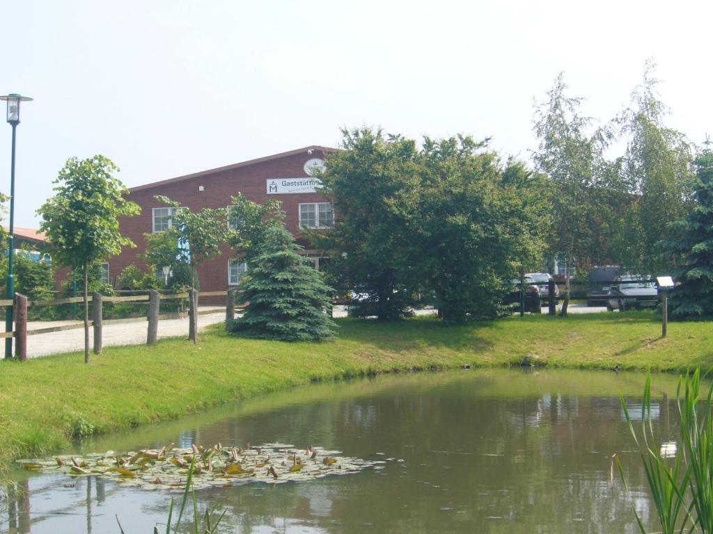 einen Teich mit Lilien im Wasser vor einem Gebäude in der Unterkunft Reitanlage Plath in Timmendorf