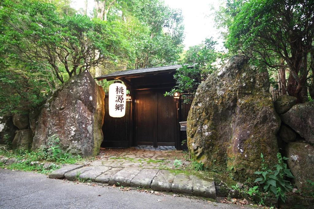 ein hölzerner Eingang zu einem Gebäude mit einem großen Felsen in der Unterkunft 箱根 -桃源郷- 036h in Hakone