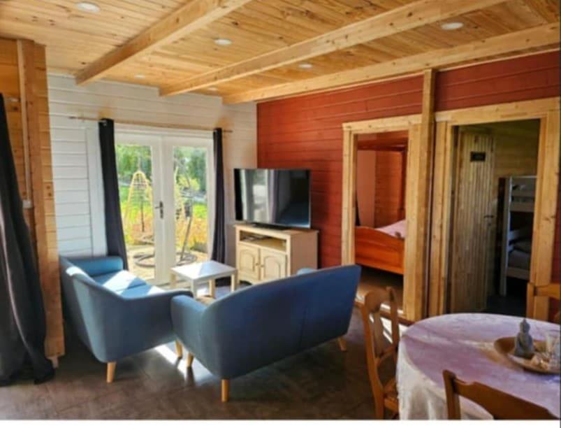 un salon avec des chaises bleues et une télévision dans l'établissement La Belle brune, avec jacuzzi, à Alincthun