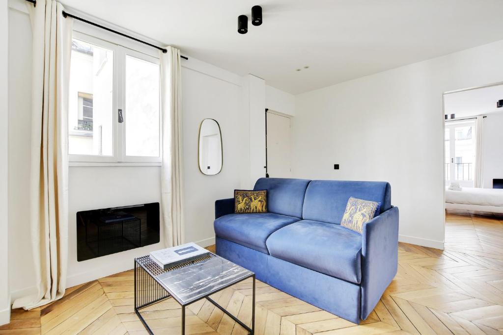 un salon avec un canapé bleu et une table dans l'établissement Pick A Flat's Apartment in Tour Eiffel - Rue du Champs de Mars, à Paris
