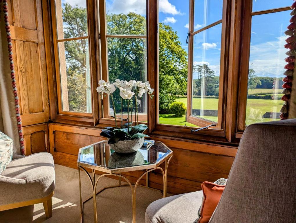 a room with a table with a vase of flowers on it at Parc-Le-Breos House in Penclawdd