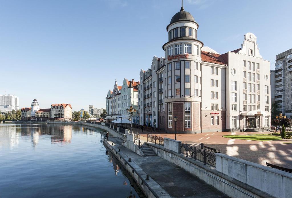 ein Gebäude mit einem Uhrturm neben einem Fluss in der Unterkunft Kaiserhof Hotel in Kaliningrad