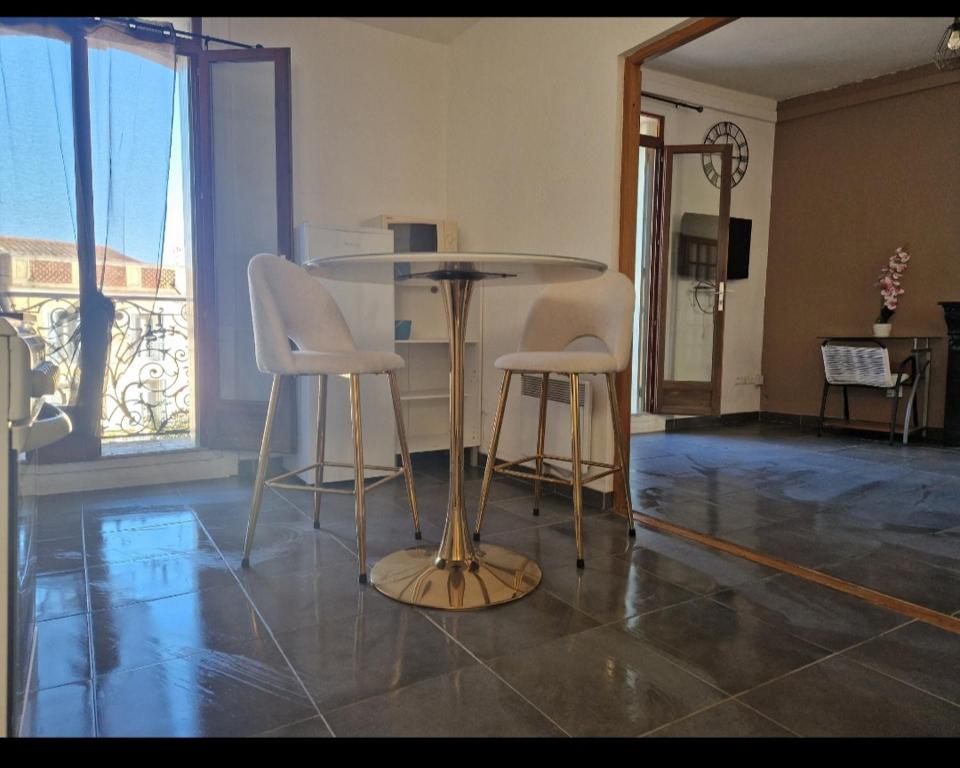 une table et deux chaises blanches dans une pièce dans l'établissement Le Petit Servian, à Servian