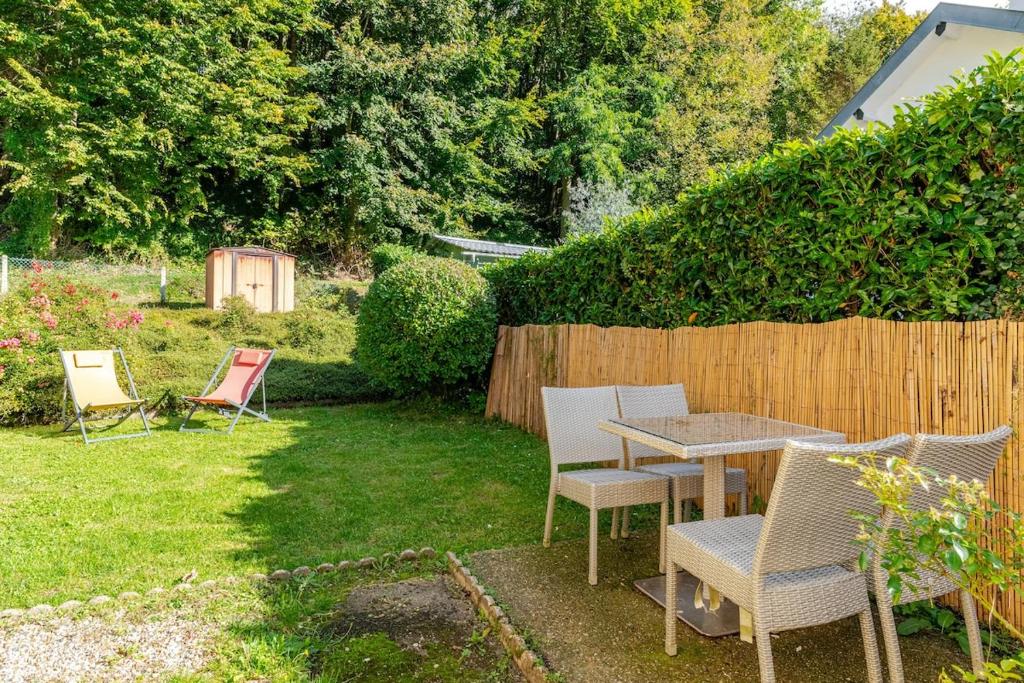 a backyard with a table and chairs and a fence at "Escapade Nature" 1 place de parking et jardin paysager by Art De Voyager in Étretat