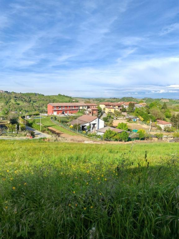 a field of green grass with buildings in the background at Appartamento con piscina - I Versanti Apartment in Alice Bel Colle