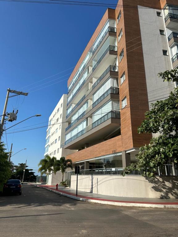 un edificio alto con una macchina parcheggiata di fronte di Piscina,sauna ,ar condicionado a 30passos da Bacutia a Guarapari