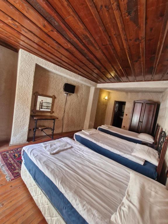 two beds in a room with a wooden ceiling at Nature Park Cave Hotel in Goreme