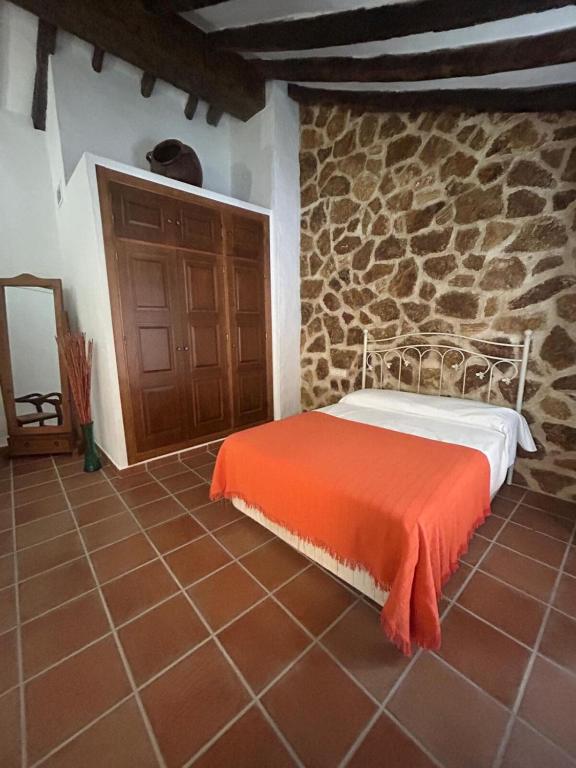 a bedroom with a bed and a stone wall at Casa Gómez in Gaucín