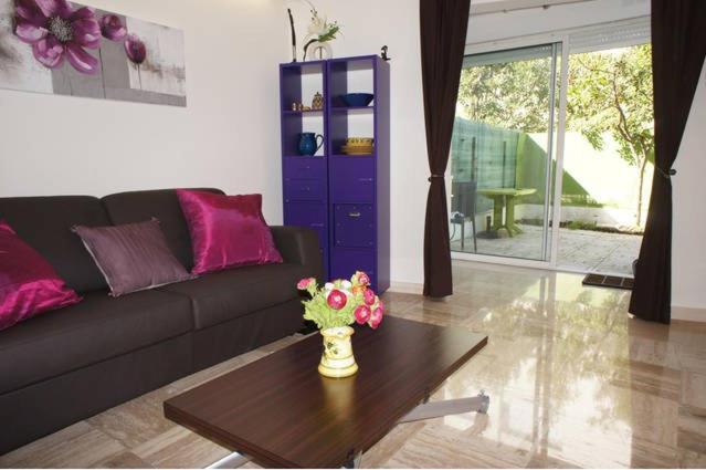 un salon avec un canapé et une table avec des fleurs dans l'établissement CANNES POINTE CROISETTE Garden & Beach, à Cannes