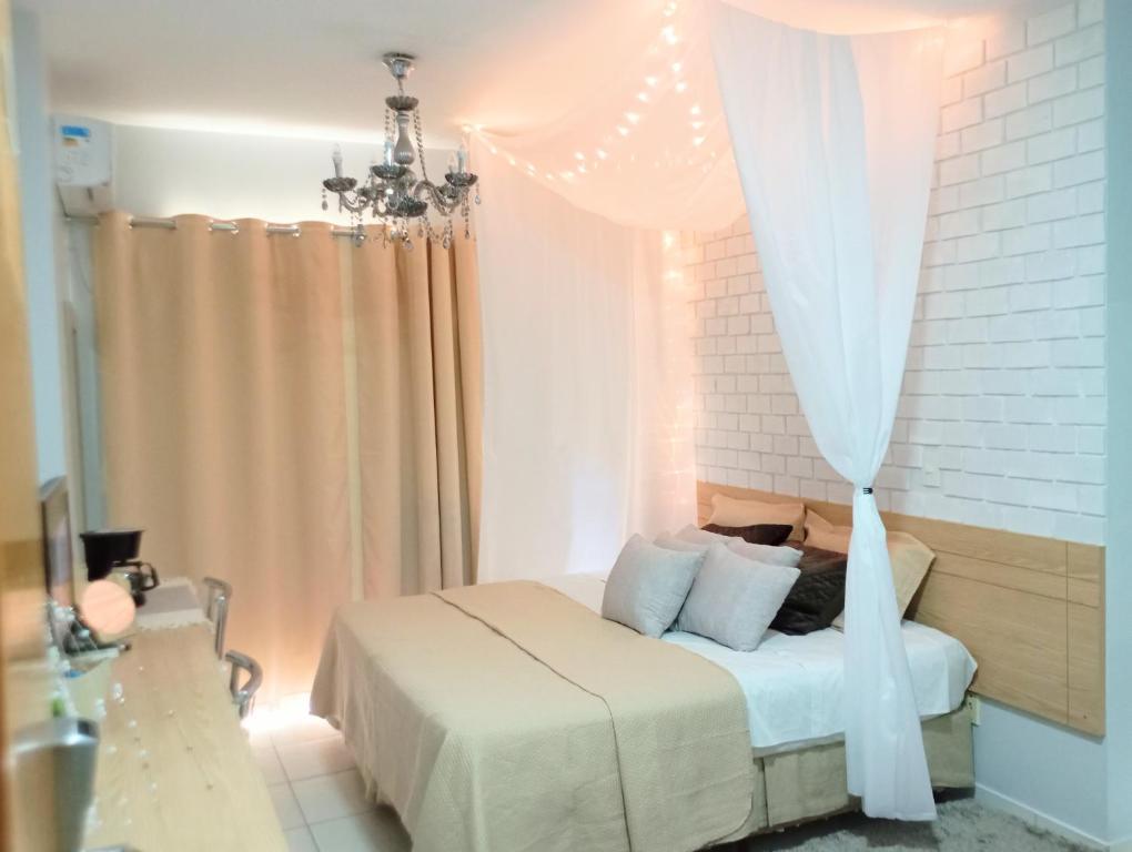 a bedroom with a white bed with a curtain at Suíte Lari in Caldas Novas
