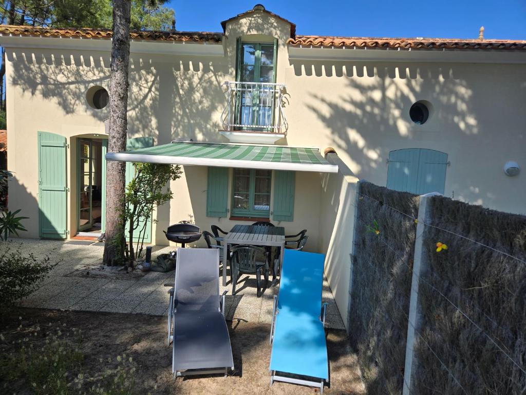a house with a table and chairs in front of it at Maison forêt et piscine, les Mas de Vertmarines in Saint-Jean-de-Monts